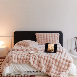 couverture d'hiver toscane rose posée sur un lit avec coussin et ordinateur portable
