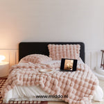 couverture d'hiver toscane rose posée sur un lit avec coussin et ordinateur portable