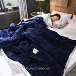 couverture en laine peluche bleu marine sur un lit avec personne endormie