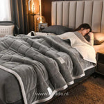 couverture en laine peluche grise sur un lit, chaleur et confort pour l'hiver