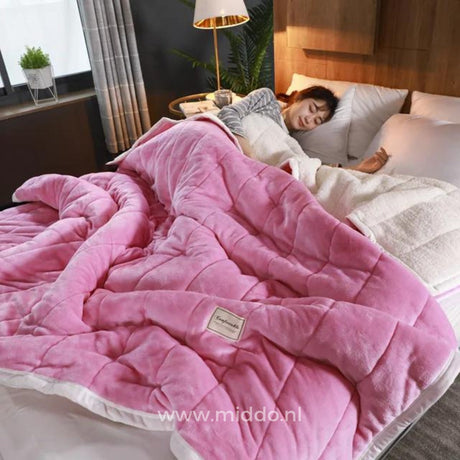 couverture en laine peluche rose pâle moelleuse sur un lit, personne endormie