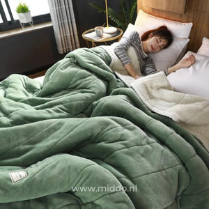 couverture en laine peluche verte sur un lit, ambiance cosy avec personne endormie