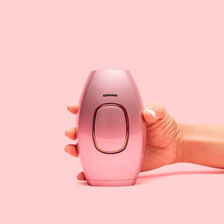 main tenant l'épilateur IPL modèle rose sur fond neutre