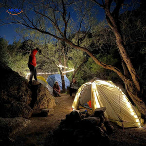 guirlande lumineuse decorative disposee autour d'une tente en pleine nature