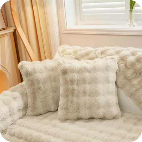 coussins et plaid blancs moelleux sur un canapé clair pour une déco lumineuse et douce