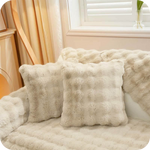 coussins et plaid blancs moelleux sur un canapé clair pour une déco lumineuse et douce