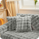 coussins et plaid gris moelleux sur un canapé près d'une fenêtre pour une ambiance hivernale
