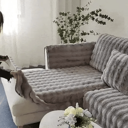 femme installant une housse de canapé grise et moelleuse sur son canapé