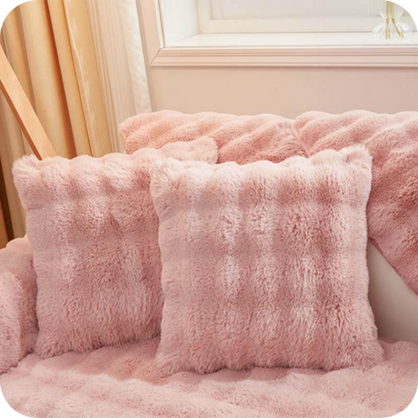 coussins et plaid roses moelleux sur un canapé près d'une fenêtre, ambiance douce et féminine