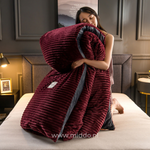 femme présentant la housse de couette en velours polaire bordeaux pliée avec la couette à l'intérieur, sur un lit