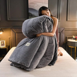 femme présentant la housse de couette en velours polaire gris pliée avec la couette à l'intérieur, sur un lit