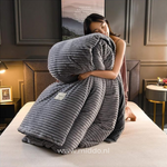 femme présentant la housse de couette en velours polaire gris pliée avec la couette à l'intérieur, sur un lit