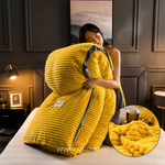 femme présentant la housse de couette en velours polaire jaune pliée avec la couette à l'intérieur, sur un lit