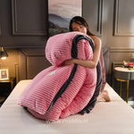 femme présentant la housse de couette en velours polaire rose pliée avec la couette à l'intérieur, sur un lit