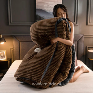 Femme tenant une housse de couette en velours polaire brun à texture côtelée et bordure foncée