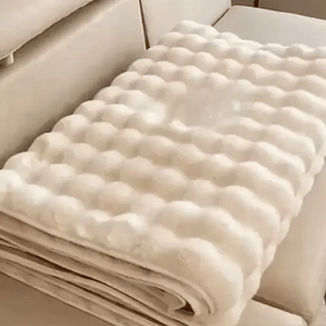 housse de meuble beige soigneusement pliée posée sur un canapé beige