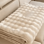 housse de meuble beige soigneusement pliée posée sur un canapé beige
