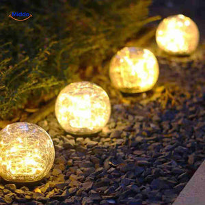 lampe solaire d'ambiance posée le long d'une allée de jardin en gravier