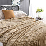 Beige fluwelen fleece kleed op een bed met kussen en bloemenvaas