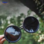 lunettes de soleil artisanales tenues à la main, reflet sombre des verres filtre ND9