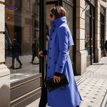 manteau bleu à coupe longue devant une vitrine de boutique en ville