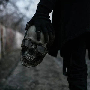 masque crâne halloween tenu à la main dans une ambiance sombre