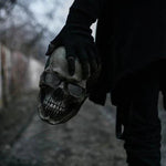 masque crâne halloween tenu à la main dans une ambiance sombre