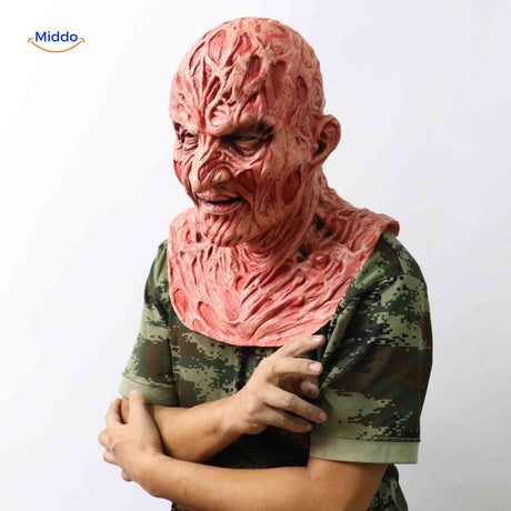 personne en chemise camouflage portant un masque zombie brûlé avec la main sur le masque