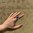 montre-bague argent avec cadran noir portée sur une main, accessoire élégant