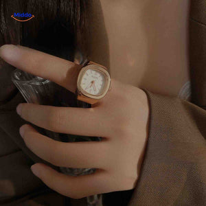 montre-bague rose avec cadran blanc portée sur une main, look féminin délicat