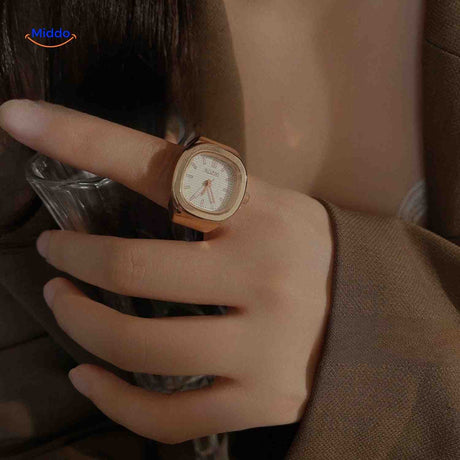 montre-bague rose avec cadran blanc portée sur une main, look féminin délicat