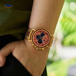 montre en bois dorée chronographe au poignet, finition or et bois naturel assortis