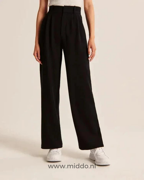 pantalon large femme noir porté avec des baskets blanches, look casual