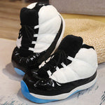 pantoufles sneakers blanc et noir avec détails bleus et semelle antidérapante, posées sur un tapis