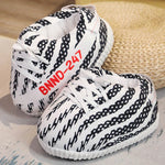 pantoufles sneakers à rayures noir et blanc avec lacets blancs, sur surface en osier
