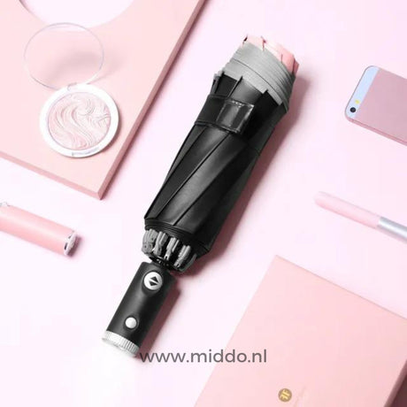 parapluie résistant au vent coloris rose posé avec un smartphone et un stylo sur fond rose