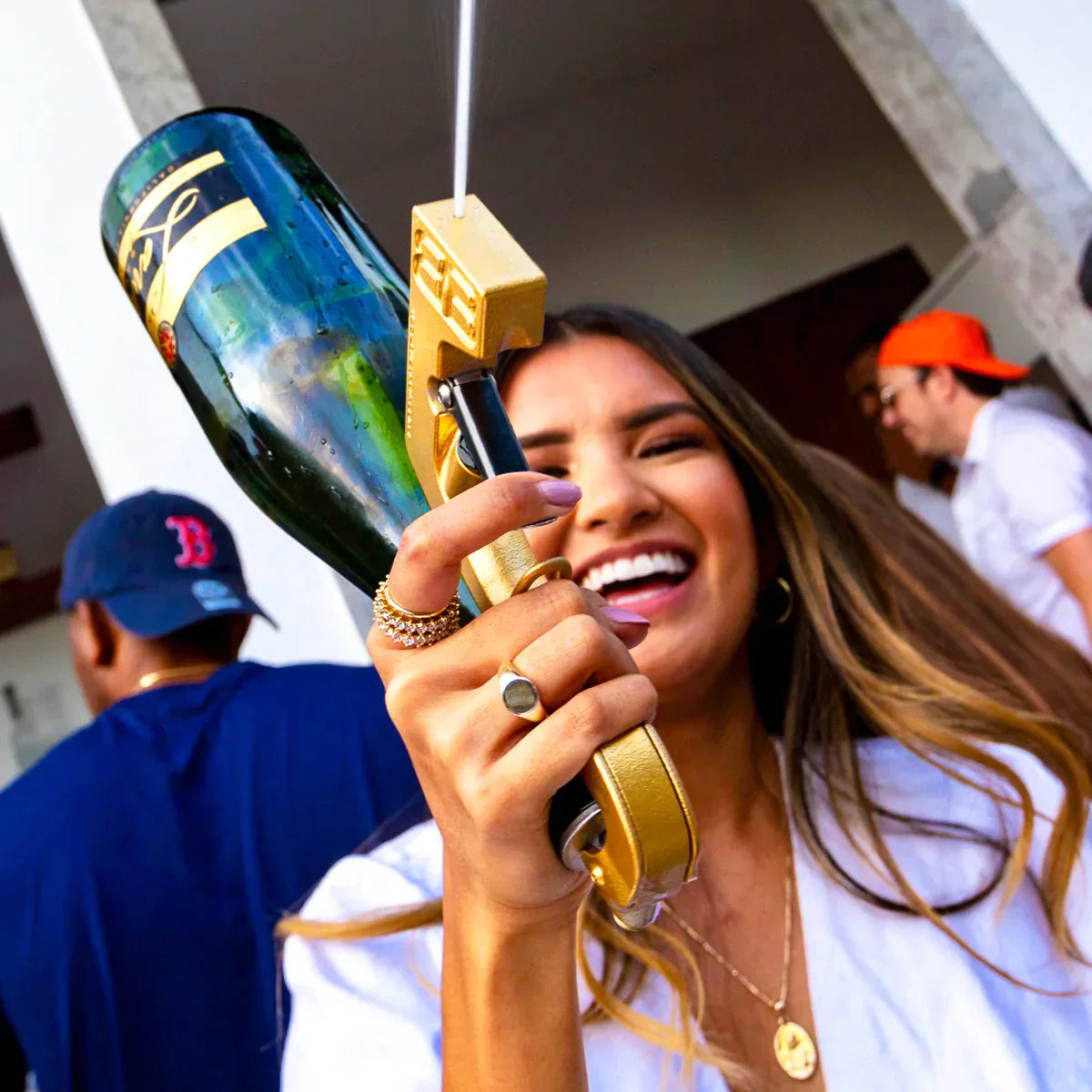 femme souriante en fête tenant un pistolet à boissons doré avec une bouteille de champagne