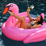 femme sur un cygne gonflable rose tenant un pistolet à boissons doré au bord de la piscine