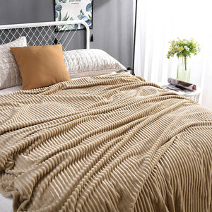 plaid en velours polaire beige posé sur un lit avec coussins et vase fleuri, ambiance cosy
