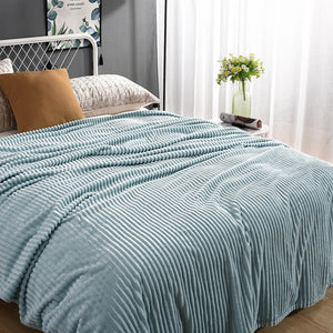 plaid en velours polaire bleu ciel sur un lit soigneusement fait avec coussin assorti