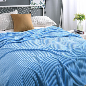 plaid en velours polaire bleu clair doux sur un lit bien préparé, coloris reposant