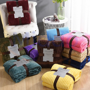 collection de plaids en velours polaire en différents coloris présentés sur fauteuil et table