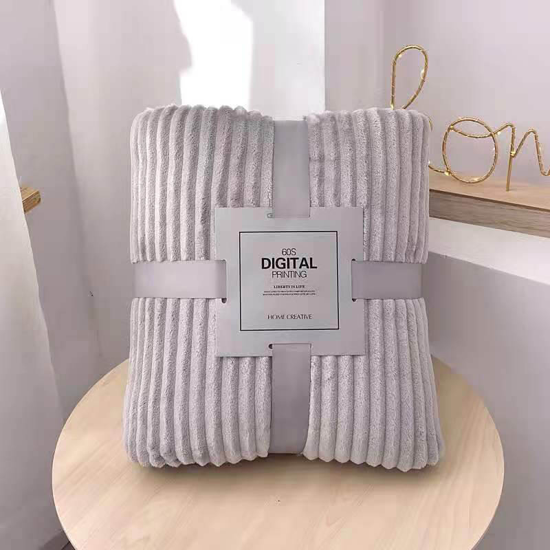 plaid en velours polaire gris présenté plié et emballé avec soin, prêt à offrir