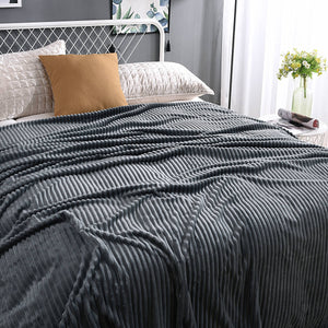 plaid en velours polaire gris anthracite élégamment disposé sur un lit bien fait