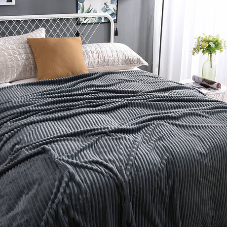 plaid en velours polaire gris anthracite élégamment disposé sur un lit bien fait