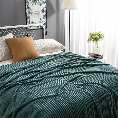 plaid en velours polaire vert foncé élégamment disposé sur un lit avec coussins assortis