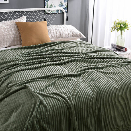 plaid en velours polaire vert apaisant sur un lit fait avec soin, toucher soyeux
