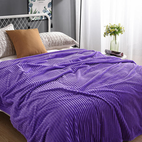 plaid en velours polaire violet doux sur un lit avec coussins et objets de décoration