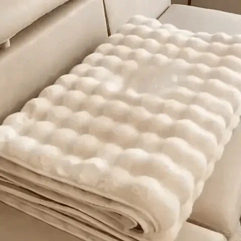 housse de meuble beige soigneusement pliée posée sur un canapé beige