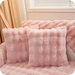 Roze pluche kussens en deken op een bank bij een raam